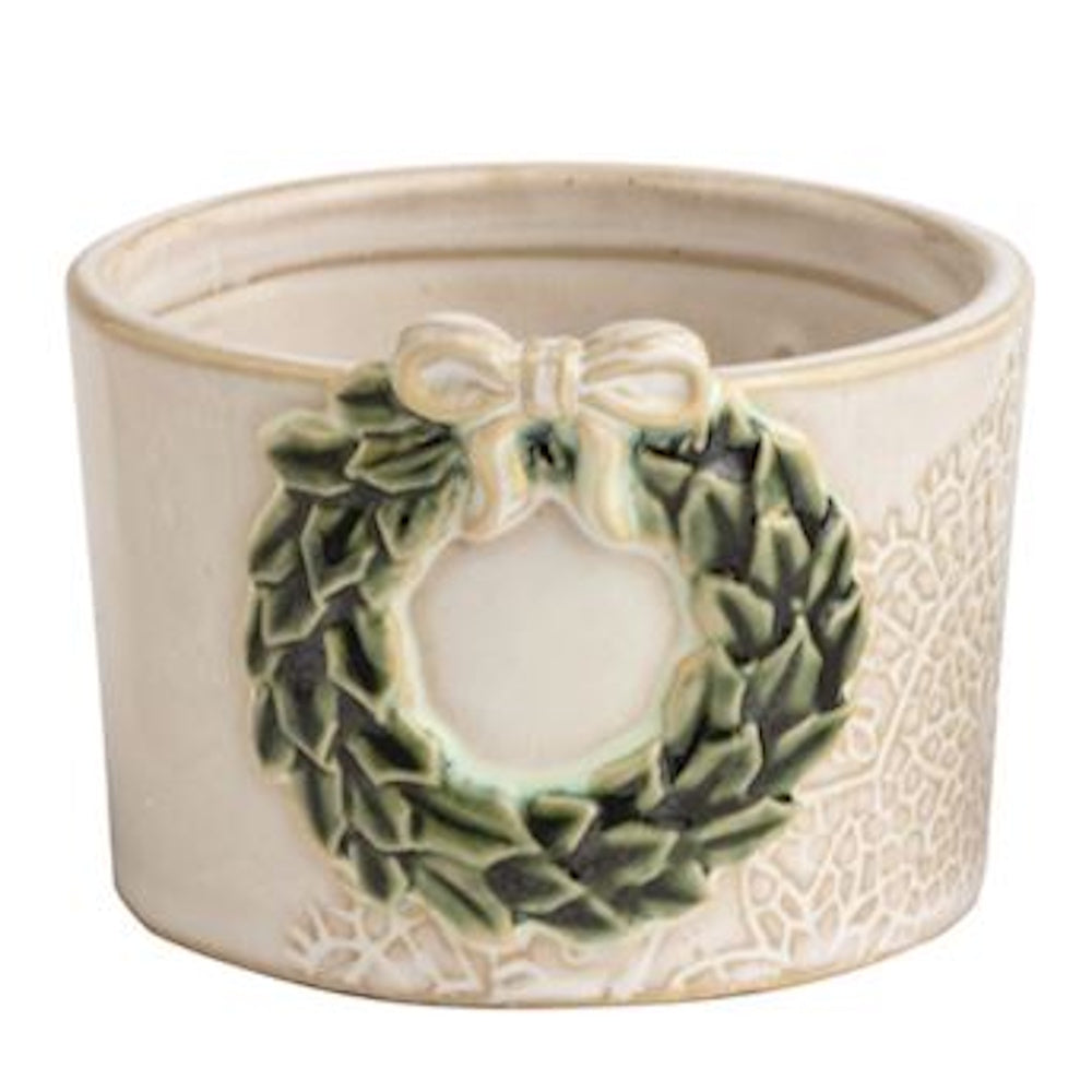 White ceramic dish decorated with a green wreath relief and cream bow on a plain background.
