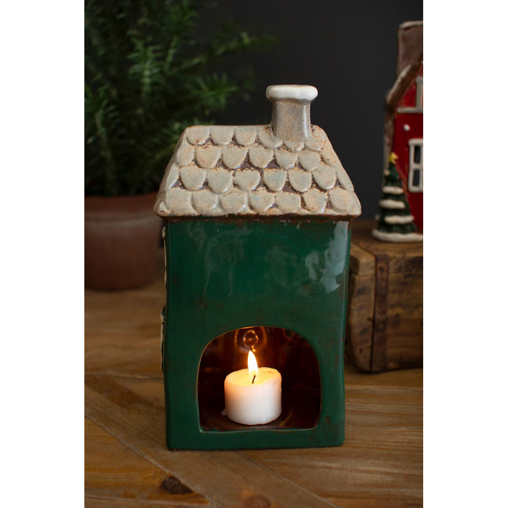 Back view of a green ceramic Christmas village house illuminated by a tea light candle.