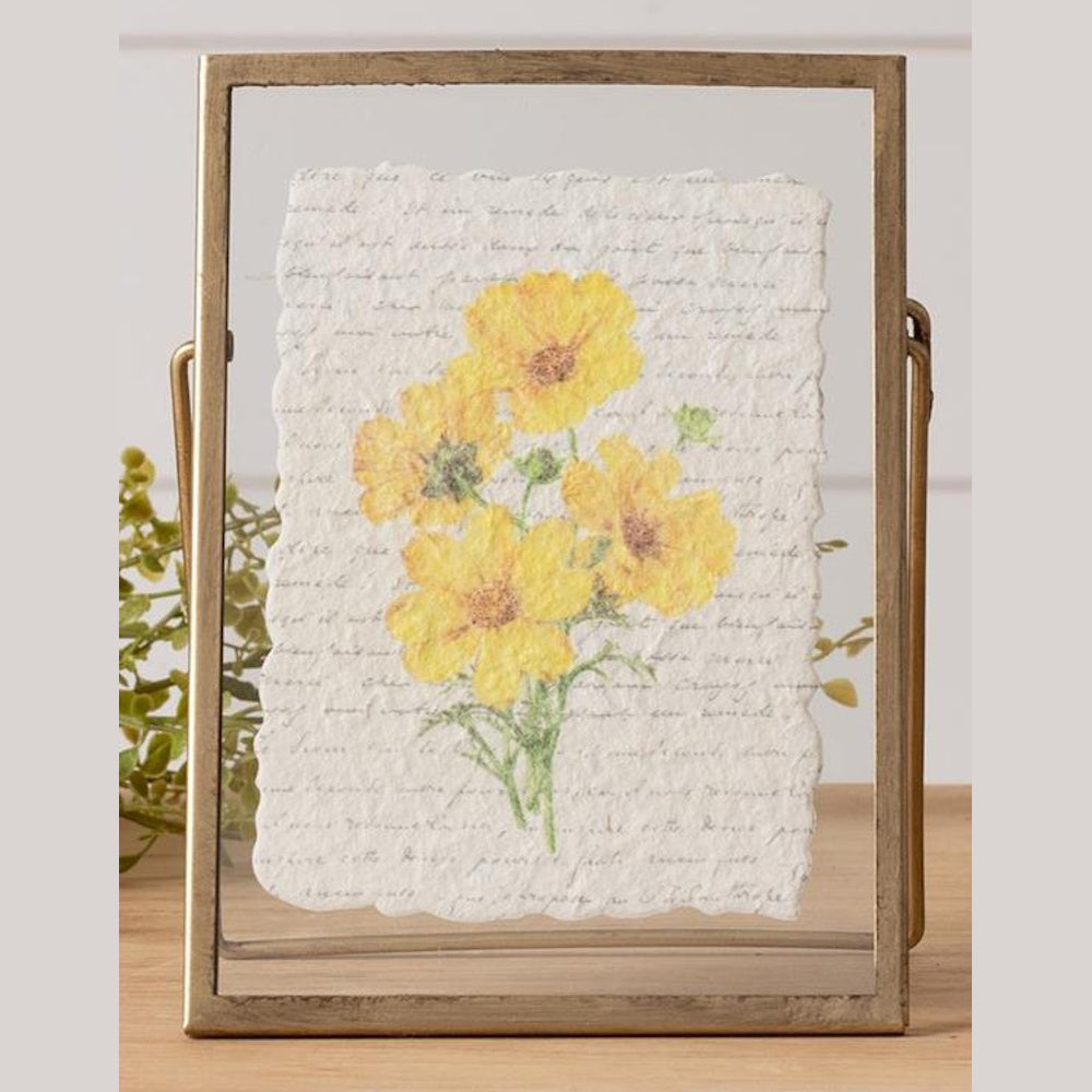 Pressed yellow flowers on deckled edge paper with script, displayed in a vintage gold floating metal frame.