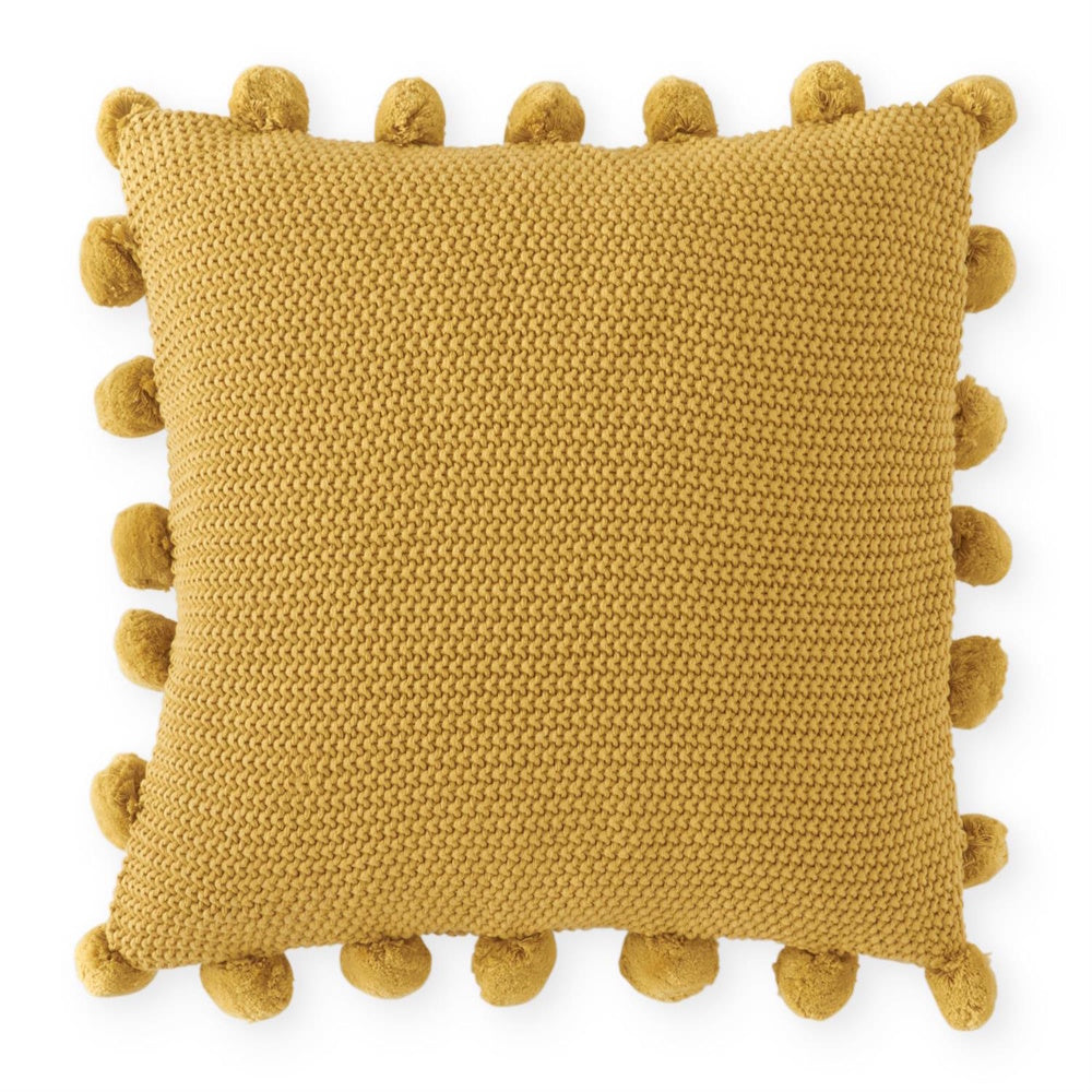 Mustard yellow moss-stitch knit throw pillow with matching pom-pom trim along the edges.